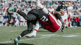 American football players engage in a tackle