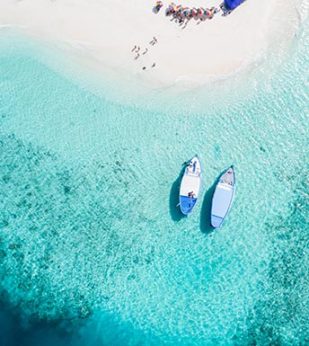 two boats anchored near crystal blue water