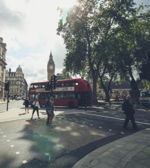 London street with a red tour bus in the foreground and Big Ben in the background