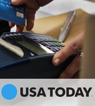 A woman slides a blue credit card through a card reader on a desk. The USA Today logo is below the image.
