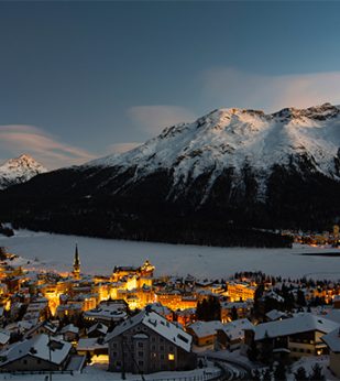 city near mountainside lit at dusk
