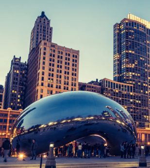 A view of Chicago's Cloud Gate at sunset with pedestrians around it.
