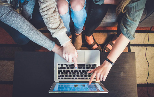 multiple people pointing to a laptop