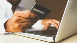 Person typing in credit card number into laptop