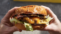 Person holding a cheese burger