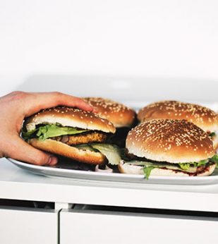 person grabbing hamburger off tray of burgers