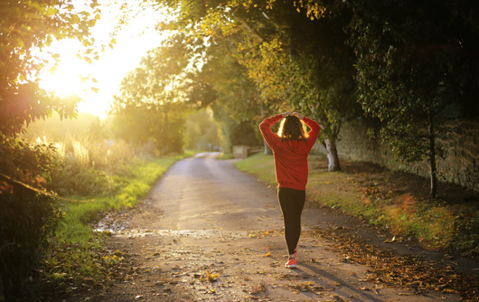 a woman walks on a country road in the morning
