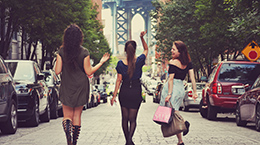 Women happily walk down the street carrying shopping bags