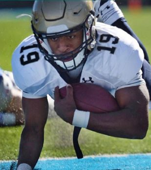 A football player dives to the ground holding the ball