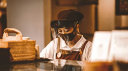 A restaurant worker preps food in a mask and face shield