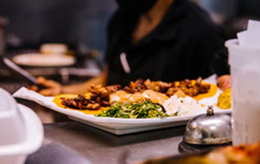 A plate of food next to a server wearing a face mask