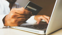 Person holds a credit card in front of a laptop