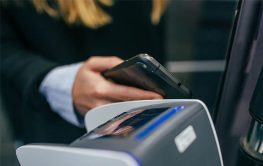 A person has their hone out while they wait at a credit card machine
