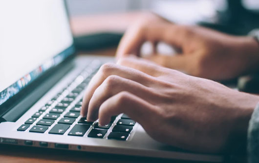 A person types on a laptop
